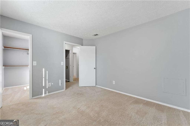 unfurnished bedroom with carpet floors, a textured ceiling, baseboards, and visible vents
