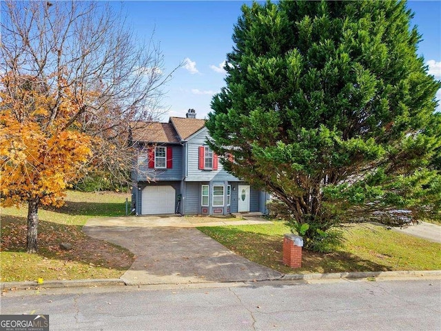 traditional home with an attached garage, a front yard, a chimney, and concrete driveway