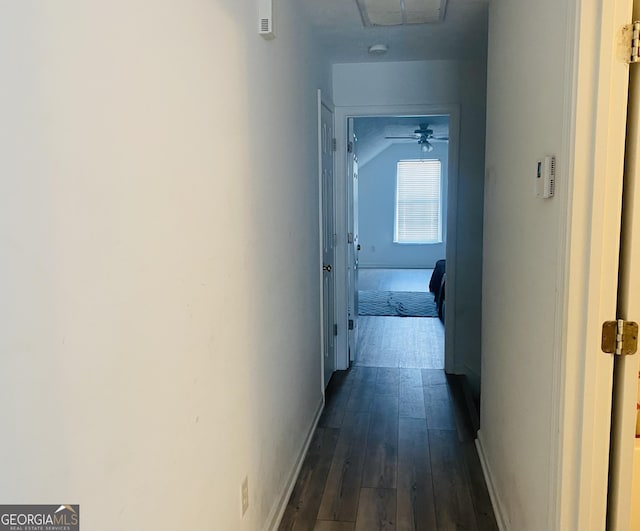hallway with baseboards, attic access, and dark wood-style flooring