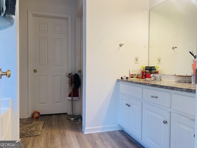 bathroom featuring baseboards, wood finished floors, and vanity