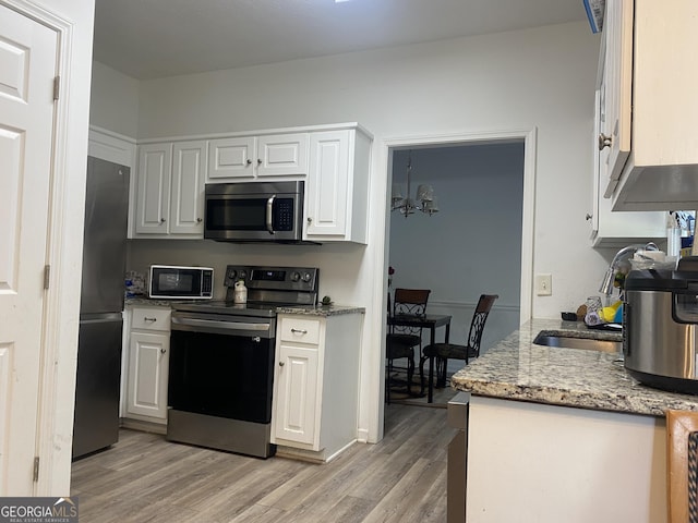 kitchen featuring light stone countertops, stainless steel appliances, light wood-type flooring, and white cabinetry