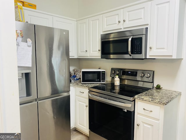 kitchen featuring light stone counters, light wood-type flooring, white cabinetry, and stainless steel appliances