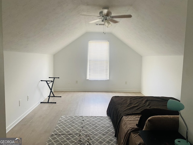 bedroom featuring wood finished floors, baseboards, ceiling fan, a textured ceiling, and vaulted ceiling