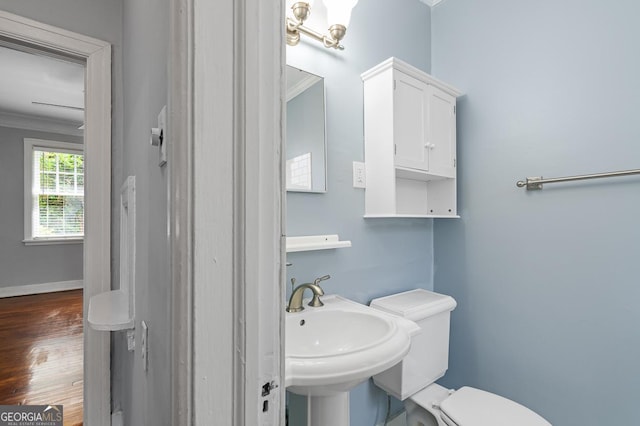 bathroom with crown molding, a sink, toilet, baseboards, and wood finished floors