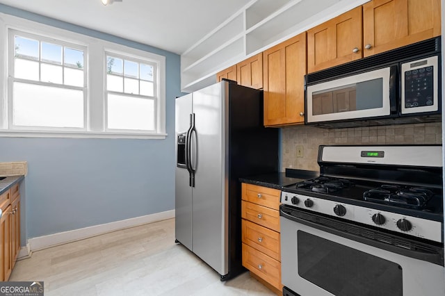 kitchen featuring decorative backsplash, brown cabinetry, gas range, dark countertops, and fridge with ice dispenser