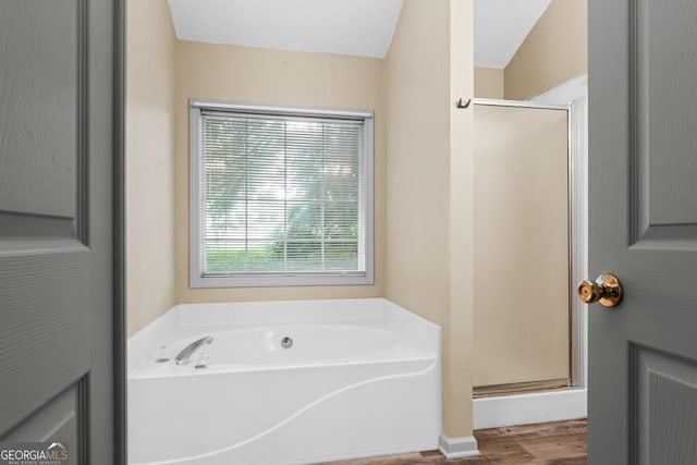 bathroom featuring a bath, wood finished floors, and a shower stall