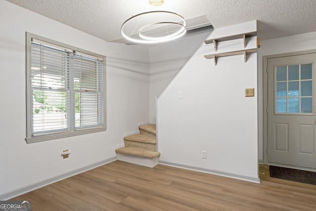 interior space featuring a textured ceiling, stairway, wood finished floors, and baseboards