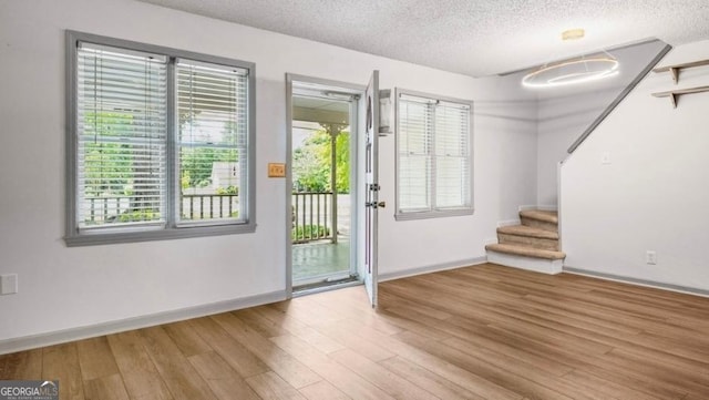 doorway with a textured ceiling, baseboards, and stairs