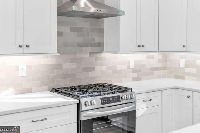 kitchen featuring tasteful backsplash, ventilation hood, stainless steel gas stove, and white cabinets