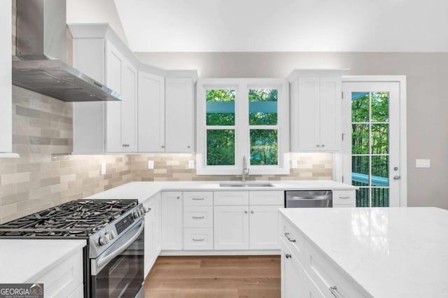 kitchen with light countertops, a sink, wall chimney exhaust hood, and stainless steel appliances