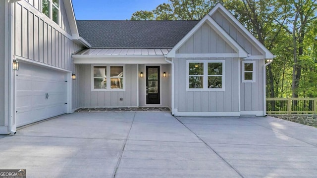 view of front of home featuring metal roof, a standing seam roof, a shingled roof, board and batten siding, and concrete driveway