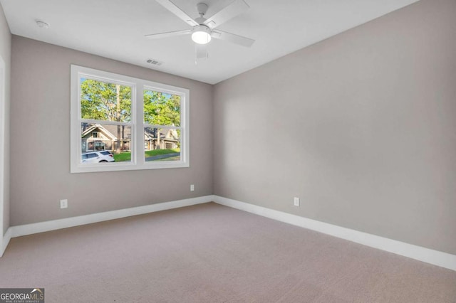 carpeted spare room with a ceiling fan, baseboards, and visible vents