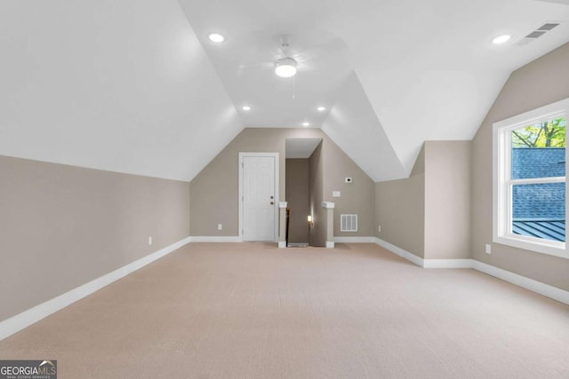additional living space featuring baseboards, light colored carpet, lofted ceiling, and visible vents