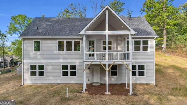 back of property with roof with shingles and a lawn