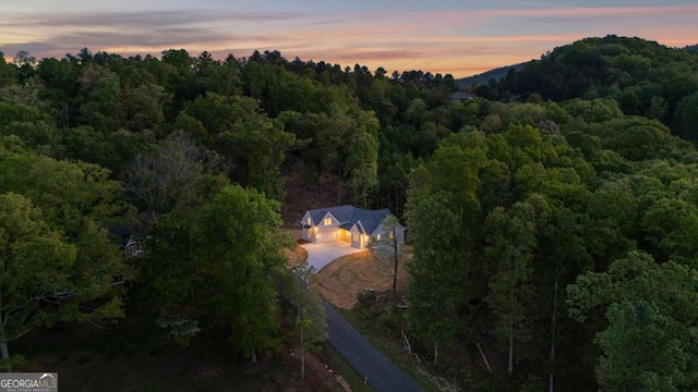 aerial view at dusk featuring a forest view