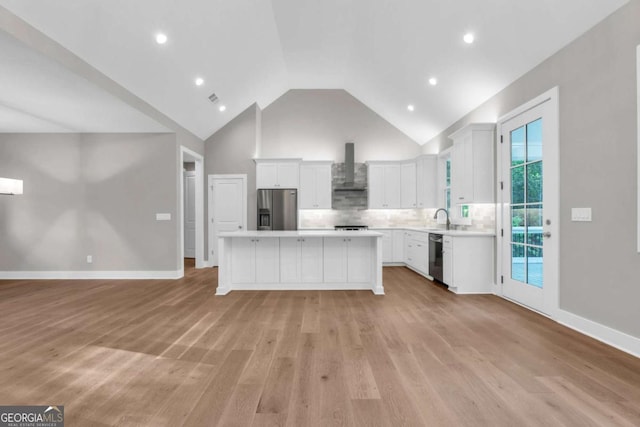kitchen featuring a center island, light countertops, high vaulted ceiling, stainless steel appliances, and wall chimney exhaust hood