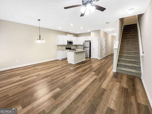6001 Oak Bend Ct, Riverdale, GA 30296 - kitchen featuring appliances with stainless steel finishes, open floor plan, a ceiling fan, white cabinetry, and a center island with sink