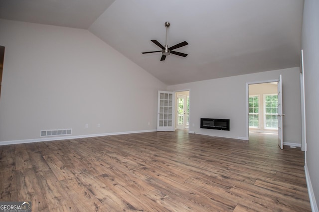 unfurnished living room with visible vents, plenty of natural light, ceiling fan, and vaulted ceiling
