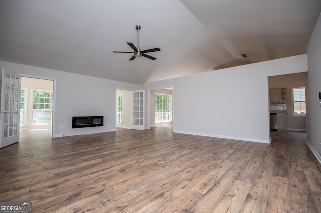 unfurnished living room featuring a ceiling fan, high vaulted ceiling, a glass covered fireplace, and wood finished floors