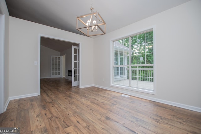 unfurnished room featuring wood-type flooring, baseboards, a notable chandelier, and visible vents