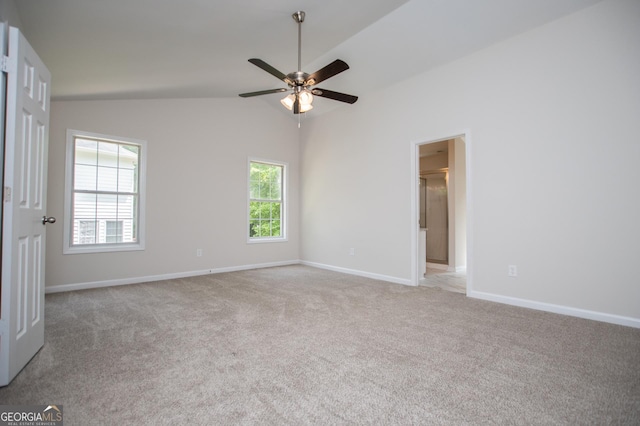 carpeted spare room with ceiling fan, vaulted ceiling, and baseboards