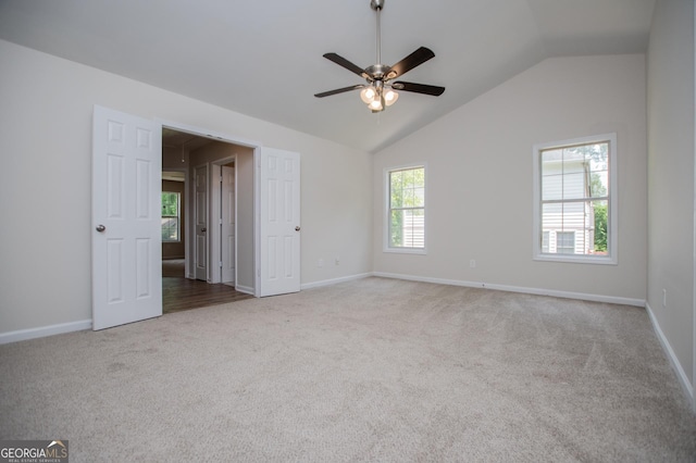 carpeted spare room with baseboards, ceiling fan, and vaulted ceiling