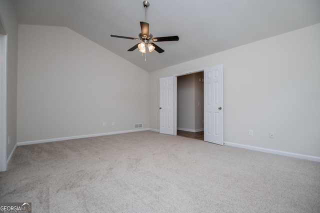 unfurnished bedroom featuring carpet floors, baseboards, vaulted ceiling, and visible vents