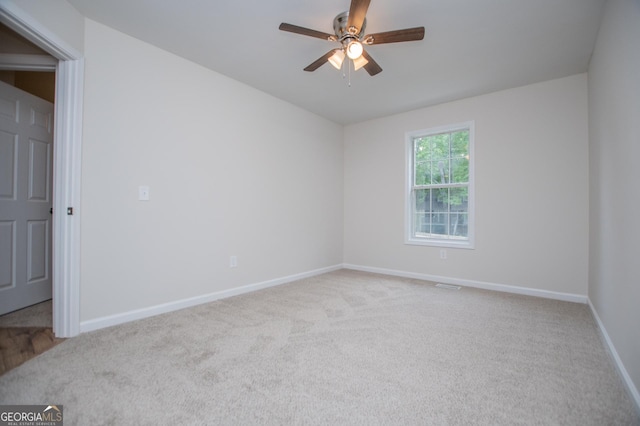 carpeted empty room with baseboards, ceiling fan, and visible vents