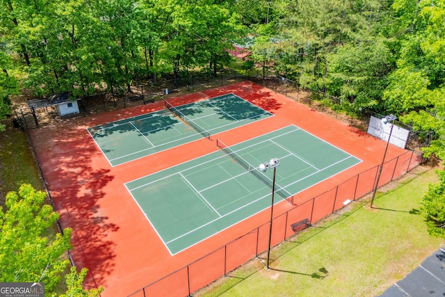 view of tennis court featuring fence and a yard