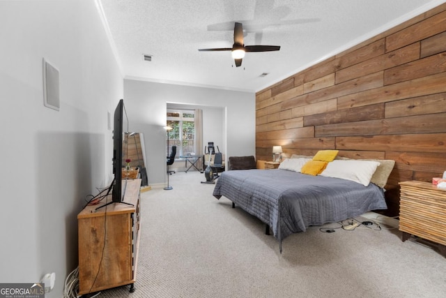 carpeted bedroom with ceiling fan, wood walls, a textured ceiling, and visible vents