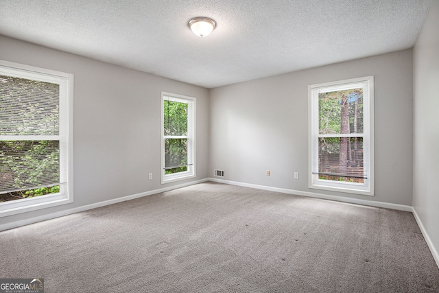 carpeted spare room featuring baseboards, a textured ceiling, and visible vents