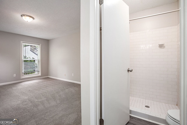 bathroom featuring baseboards, a stall shower, toilet, and a textured ceiling