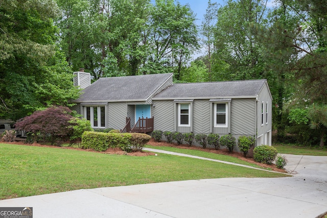 ranch-style house with driveway, a chimney, a shingled roof, and a front yard
