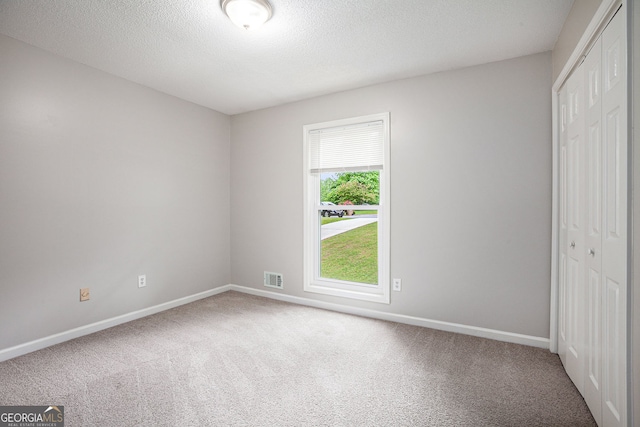 unfurnished bedroom with visible vents, carpet flooring, baseboards, and a closet