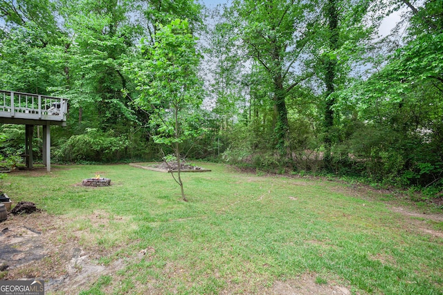 view of yard with a wooden deck and a fire pit