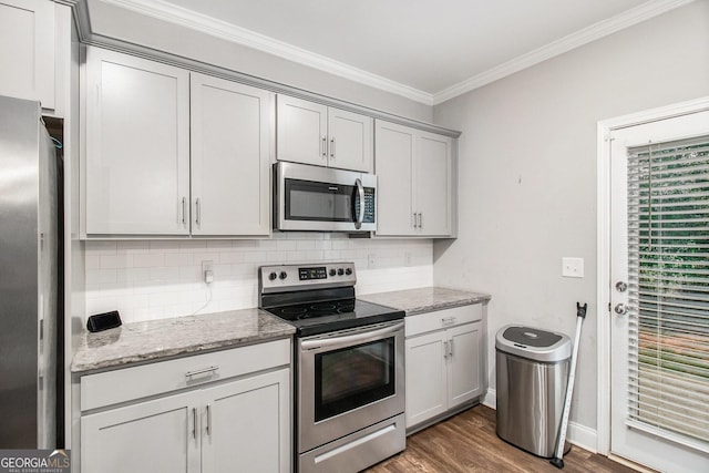 7762 Fawn Cir, Covington, GA 30014 - kitchen with appliances with stainless steel finishes, tasteful backsplash, ornamental molding, dark wood-style floors, and light stone counters