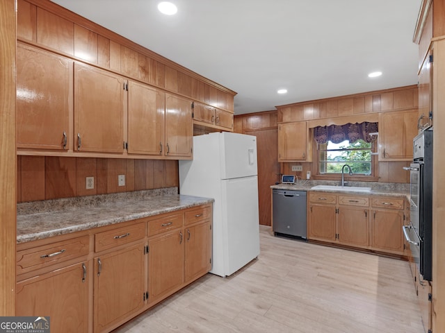 kitchen with a sink, light countertops, light wood-style floors, a warming drawer, and stainless steel appliances