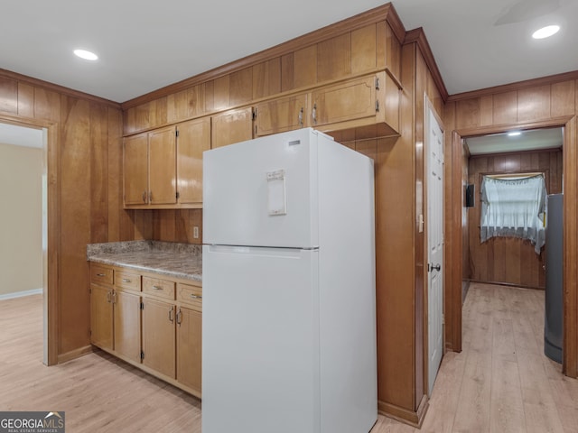 kitchen with light wood-type flooring, light countertops, freestanding refrigerator, wooden walls, and recessed lighting
