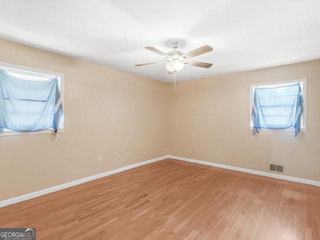 spare room with visible vents, light wood finished floors, ceiling fan, and baseboards