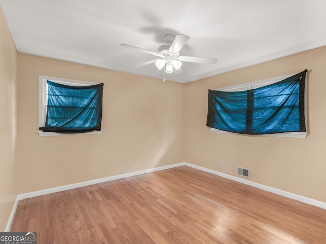 spare room with baseboards, ceiling fan, wood finished floors, and visible vents