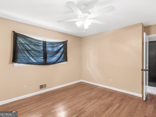 unfurnished room with baseboards, ceiling fan, wood finished floors, and visible vents