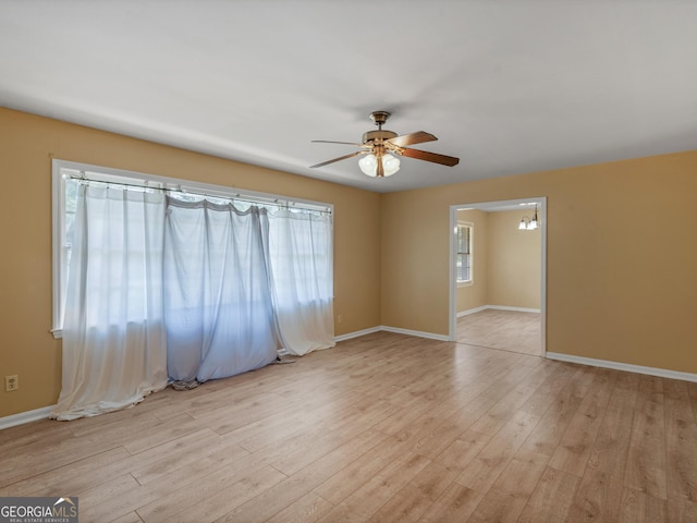 empty room with a ceiling fan, baseboards, and light wood-type flooring