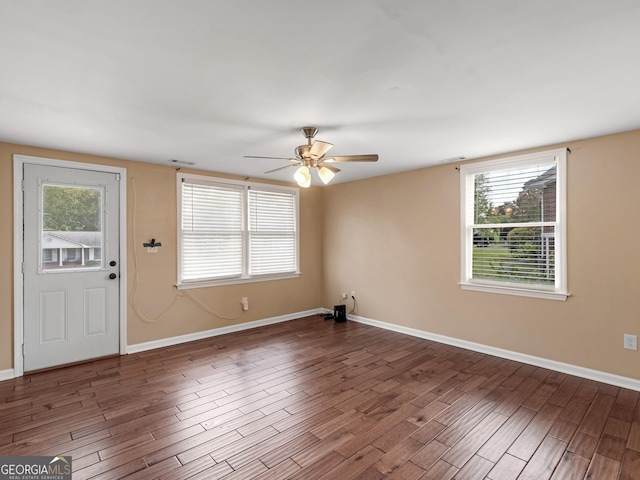 interior space featuring baseboards, ceiling fan, a wealth of natural light, and wood finished floors