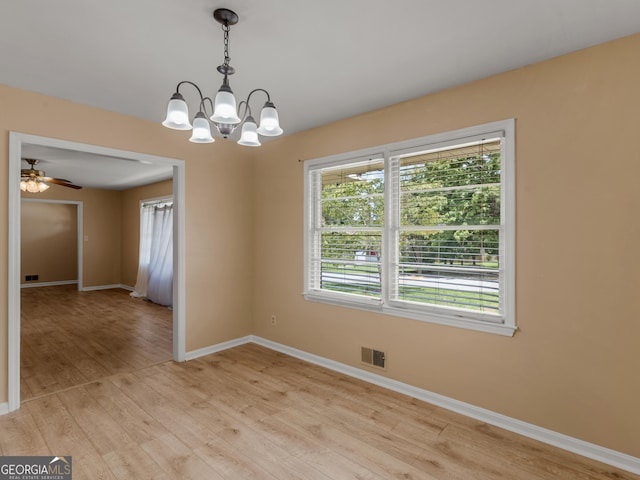 unfurnished room featuring visible vents, light wood-style floors, ceiling fan with notable chandelier, and baseboards