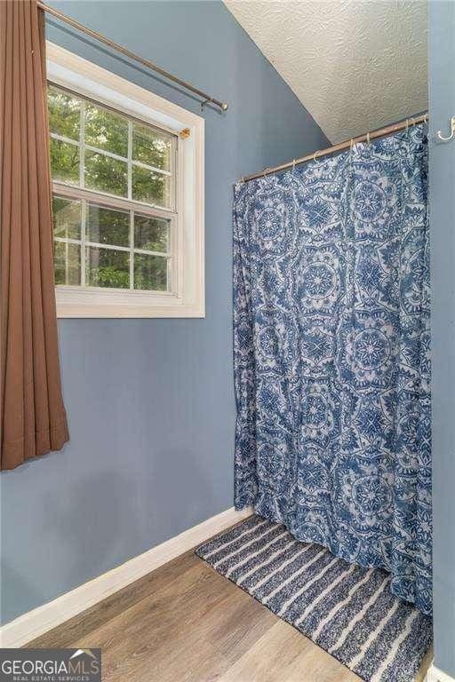 204 Queensbury Ct, Acworth, GA 30102 - bathroom featuring a shower with curtain, baseboards, a textured ceiling, and wood finished floors
