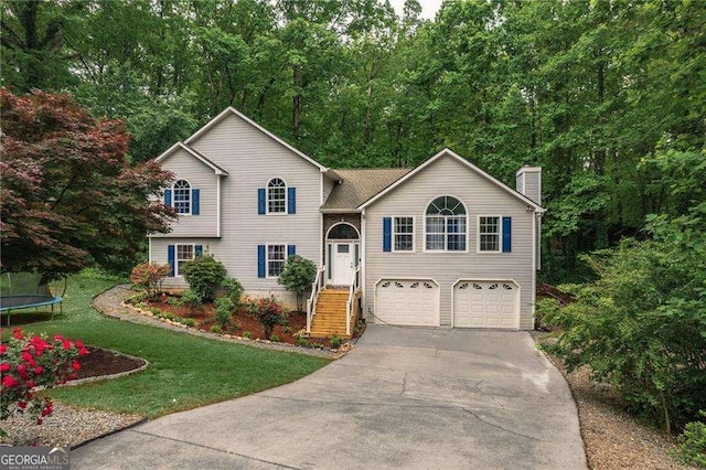 204 Queensbury Ct, Acworth, GA 30102 - view of front of property featuring a trampoline, a garage, a front yard, a chimney, and concrete driveway