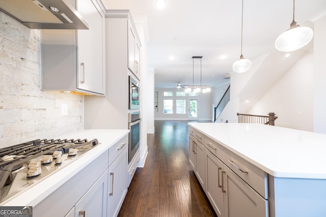 915 Katie Kerr Dr, Decatur, GA 30030 - kitchen with dark wood-style flooring, appliances with stainless steel finishes, backsplash, decorative light fixtures, and under cabinet range hood