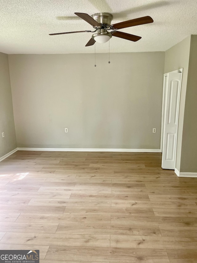 empty room featuring light wood-style floors, a ceiling fan, and a textured ceiling