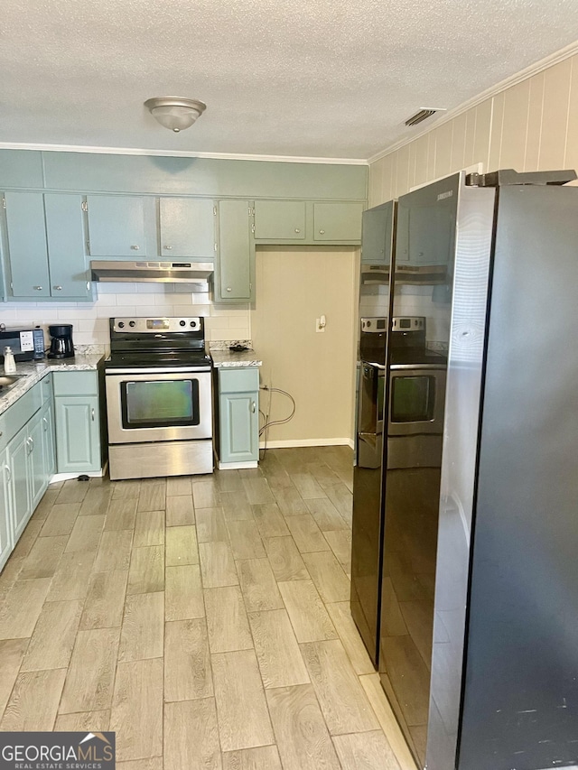 kitchen featuring ornamental molding, stainless steel appliances, a textured ceiling, and under cabinet range hood