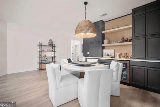 dining area with visible vents, wine cooler, baseboards, a bar, and light wood-style floors